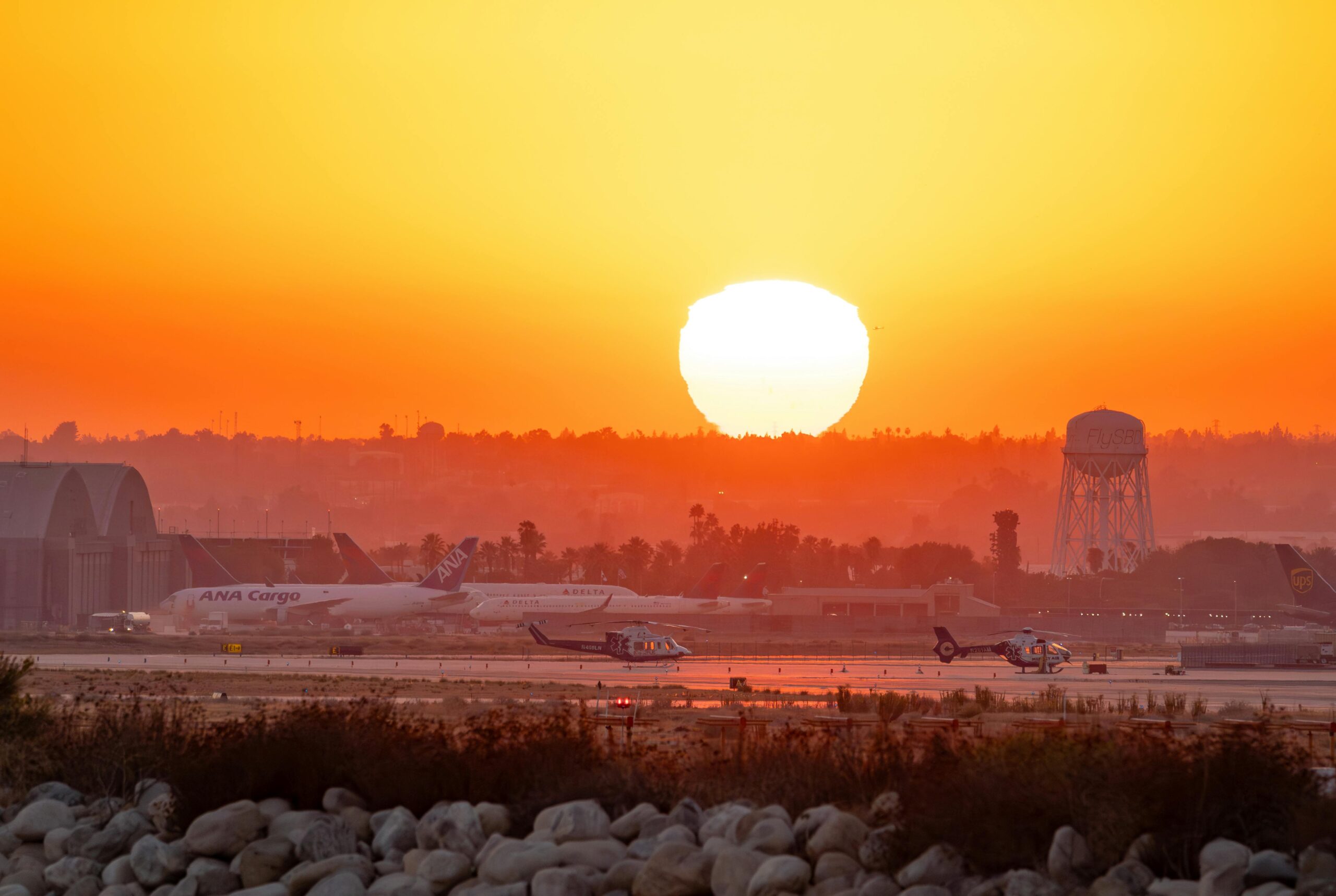 Stunning sunset at San Bernardino Airport with planes and vibrant sky.