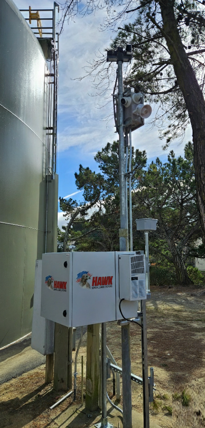 Hawk mobile surveillance system installed beside a commercial building with pole-mounted cameras and speakers