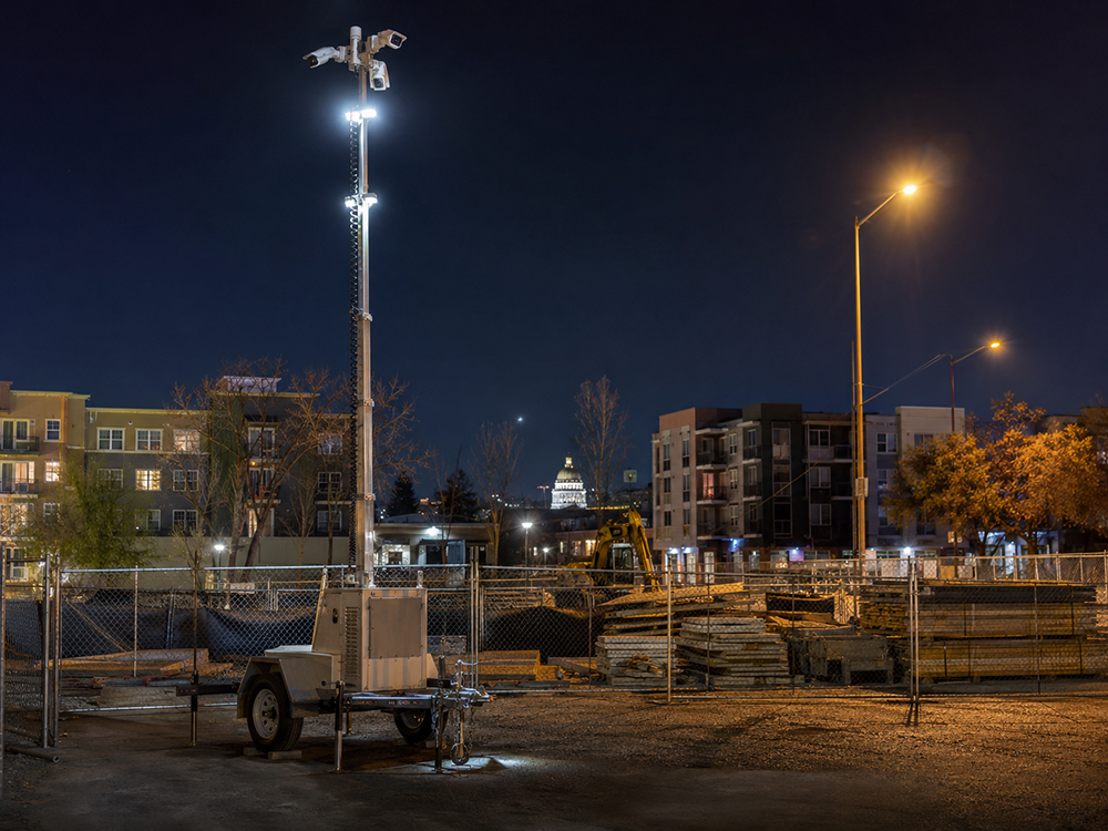 Mobile surveillance trailer covering a Sacramento construction site perimeter and material staging zone at dusk