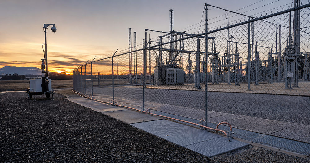 NorCal substation with surveillance trailer monitoring ground-mat perimeter at dawn