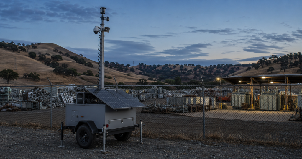 Solar mobile surveillance trailer securing a Northern California scrap-metal recycling yard at night.